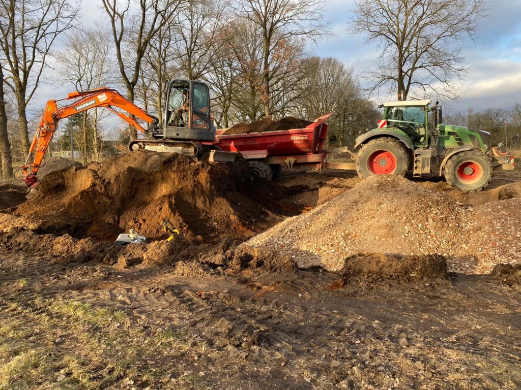 Bagger belädt Schlepper mit Holz und Grünschnitt